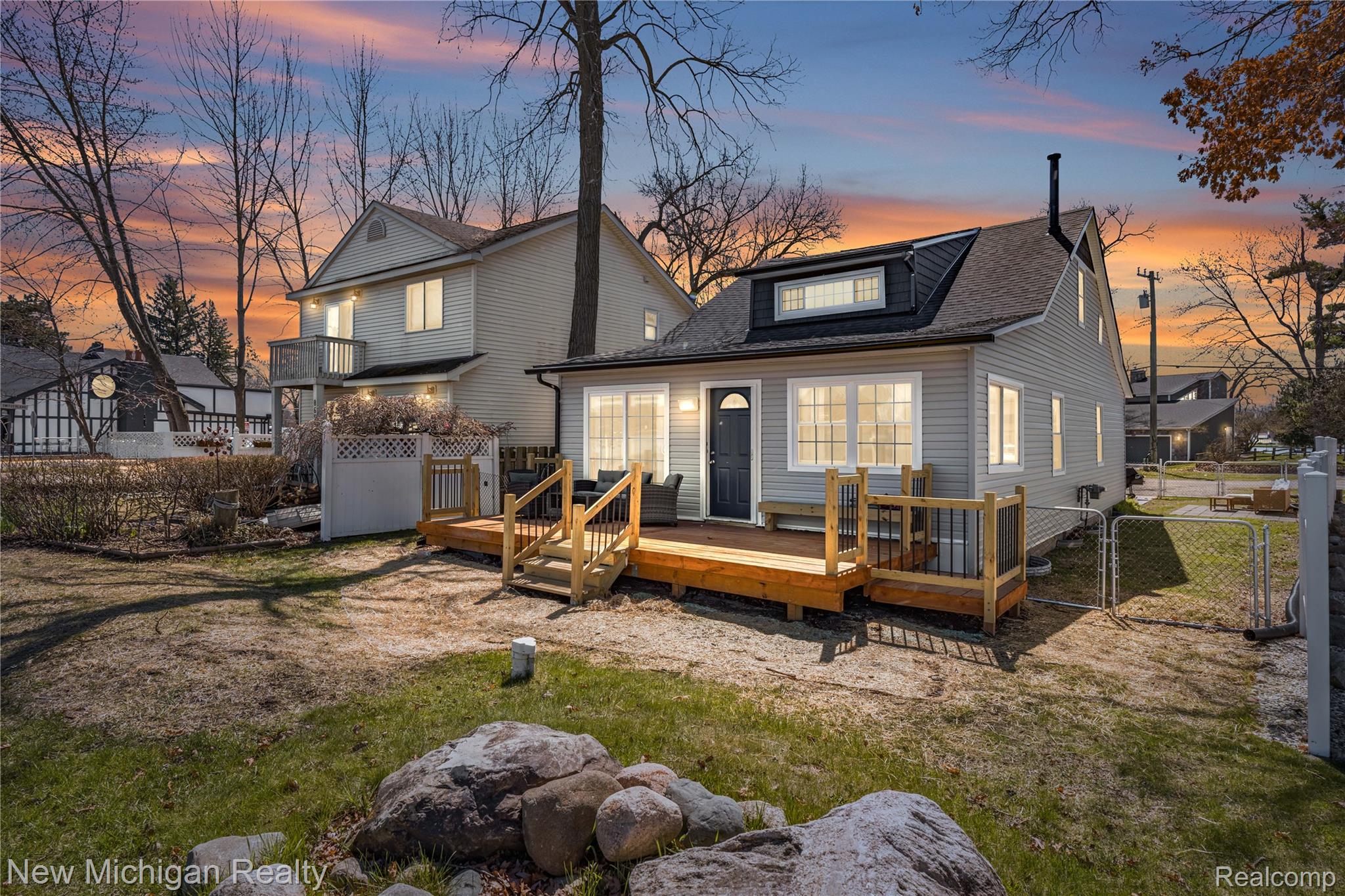 8665 Cooley Lake Road Commerce Township, MI 48382 - Photo 4 of 52 Back of house at dusk with a gate, a wooden deck, and a shingled roof