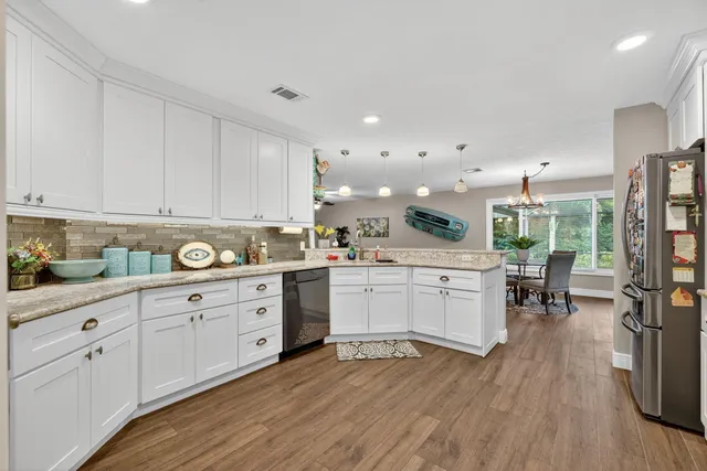 a kitchen with granite countertop a refrigerator stove and white cabinets