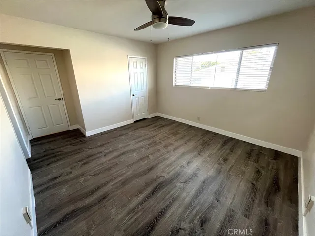 an empty room with wooden floor cabinet and windows