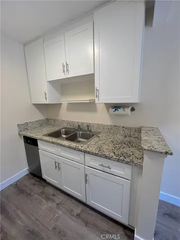 a kitchen with granite countertop white cabinets and a sink