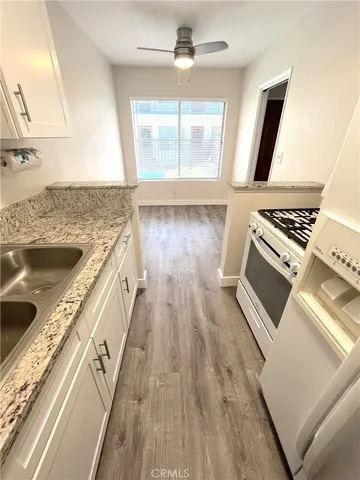 a kitchen with a stove a sink and a wooden floor