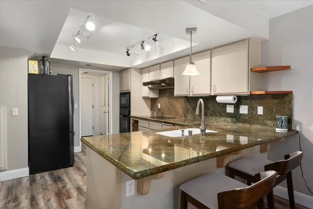 a kitchen with stainless steel appliances granite countertop a sink refrigerator and cabinets
