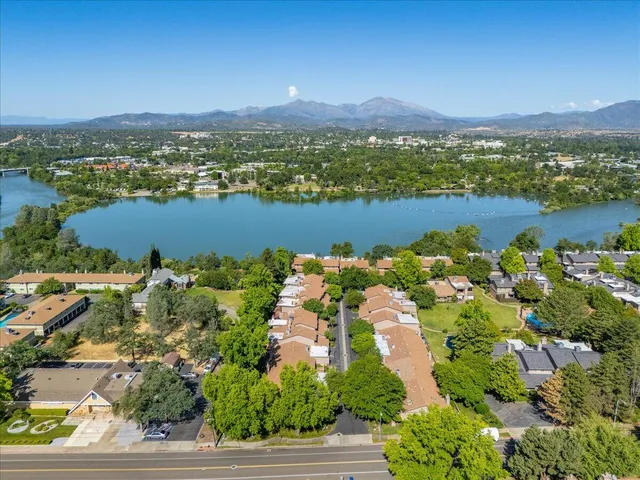an aerial view of city and lake with trees all around