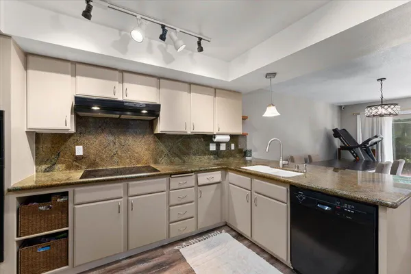 a kitchen with a sink dishwasher and white cabinets with wooden floor
