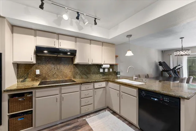 a kitchen with a sink dishwasher and white cabinets with wooden floor