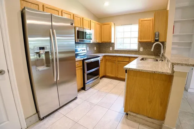 a kitchen with stainless steel appliances granite countertop a refrigerator a sink a stove and cabinets