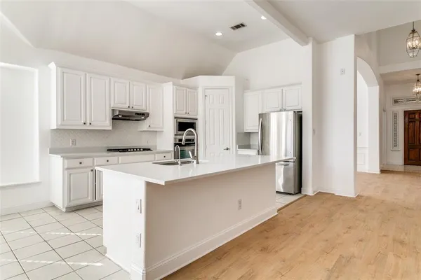 a kitchen with stainless steel appliances granite countertop a refrigerator sink and white cabinets