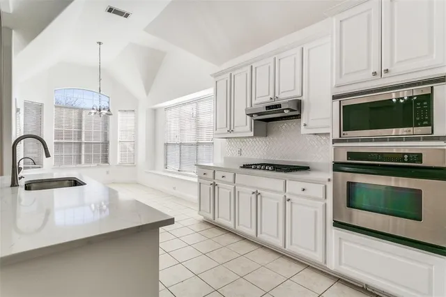 a kitchen with stainless steel appliances granite countertop a stove a sink and white cabinets