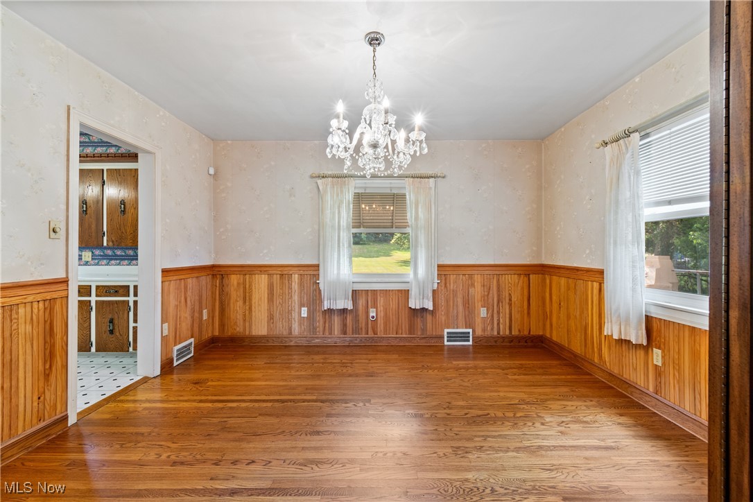3550 Manchester Road Akron, OH 44319 - Photo 8 of 40 Unfurnished dining area with a wealth of natural light, an inviting chandelier, and wood-type flooring