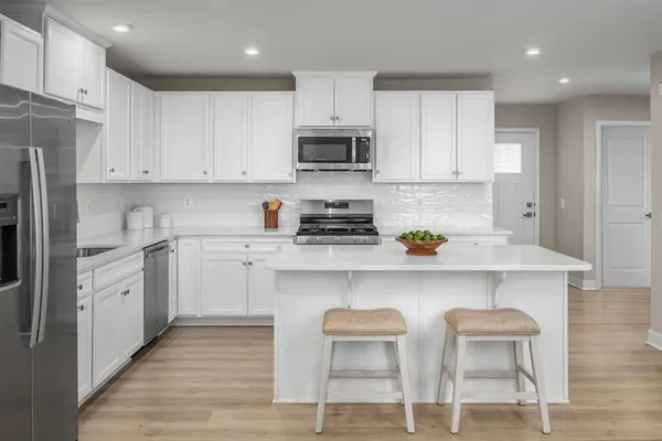 a kitchen with stainless steel appliances granite countertop a stove a sink dishwasher and a refrigerator with wooden floor