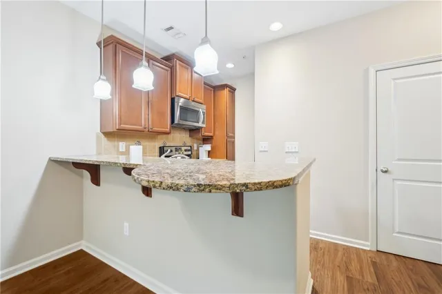 a kitchen with stainless steel appliances granite countertop a sink and a wooden floor