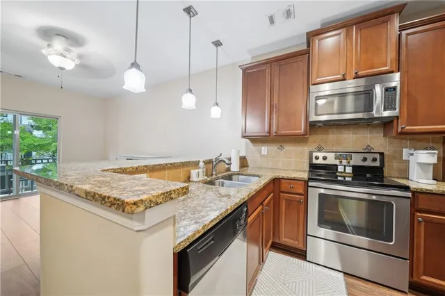 a kitchen with stainless steel appliances granite countertop a stove a sink and a microwave