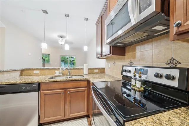 a kitchen with kitchen island granite countertop a stove a sink and a microwave