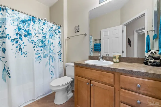 a bathroom with a granite countertop sink a toilet and a mirror