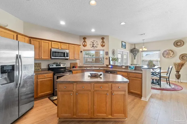 a kitchen with stainless steel appliances granite countertop a sink a stove a refrigerator cabinets and living room view