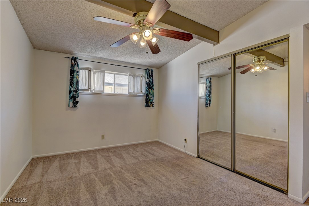 6309 Rassler Avenue Las Vegas, NV 89107 - Photo 12 of 19 Unfurnished bedroom featuring a textured ceiling, light carpet, ceiling fan, and a closet
