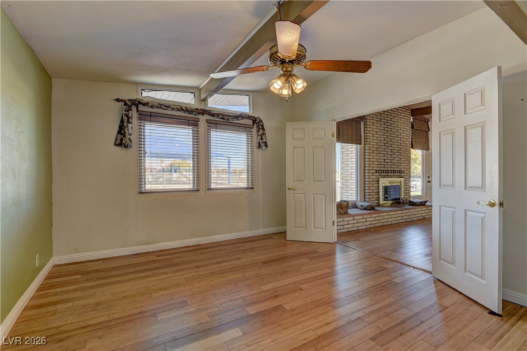 6309 Rassler Avenue Las Vegas, NV 89107 - Photo 5 of 19 Spare room with beam ceiling, light wood-style flooring, a brick fireplace, and ceiling fan