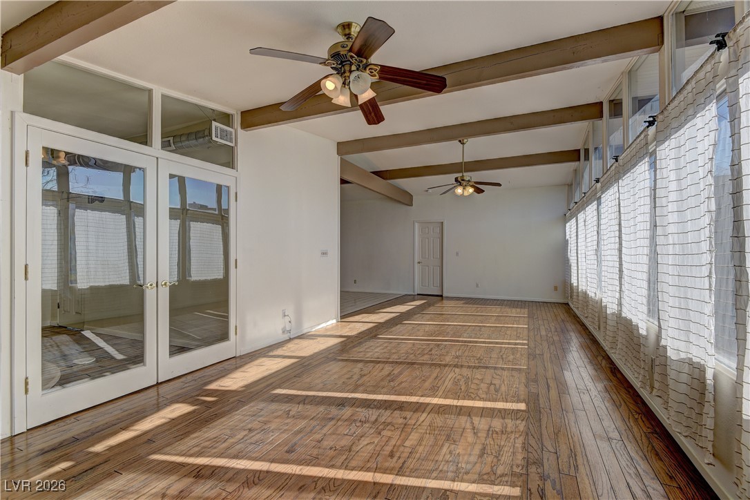 6309 Rassler Avenue Las Vegas, NV 89107 - Photo 8 of 19 Unfurnished room with beam ceiling, plenty of natural light, french doors, ceiling fan, and hardwood / wood-style flooring