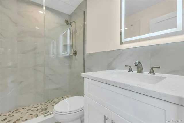 a bathroom with a granite countertop sink toilet and shower