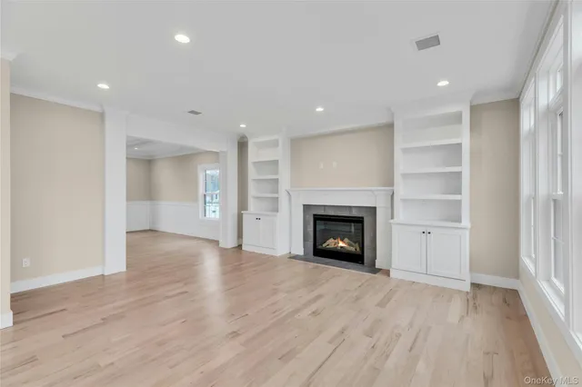 a view of an empty room with wooden floor fireplace and a window