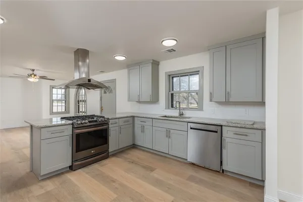 a kitchen with granite countertop a sink stainless steel appliances and window