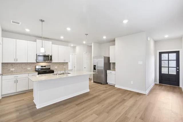 a large kitchen with stainless steel appliances kitchen island a large counter top and a stove top oven