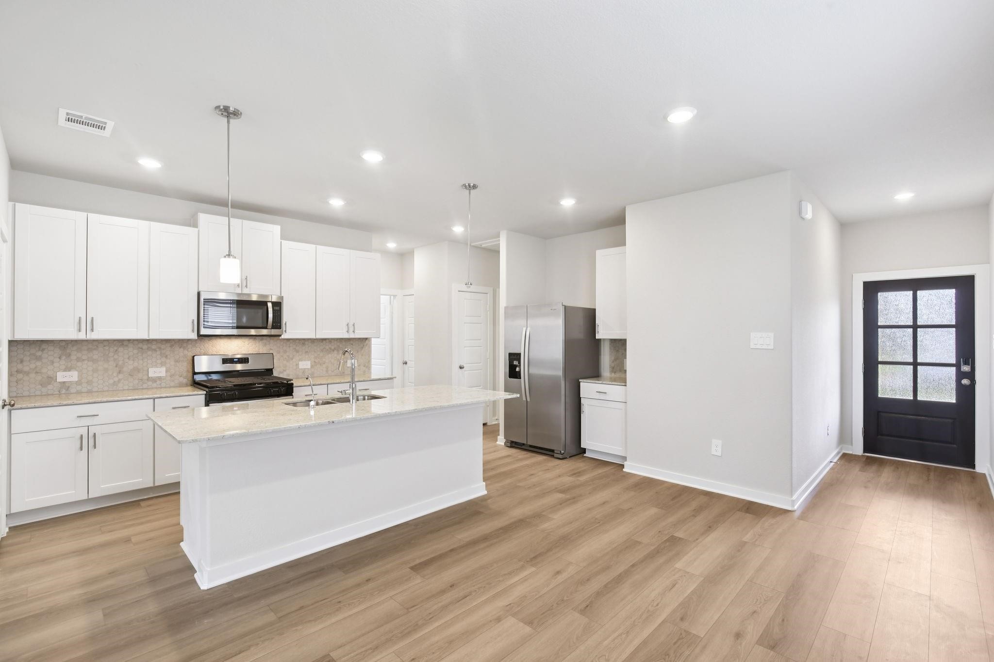 6717 Chinapkin Lane Conroe, TX 77304 - Photo 4 of 15 a large kitchen with stainless steel appliances kitchen island a large counter top and a stove top oven