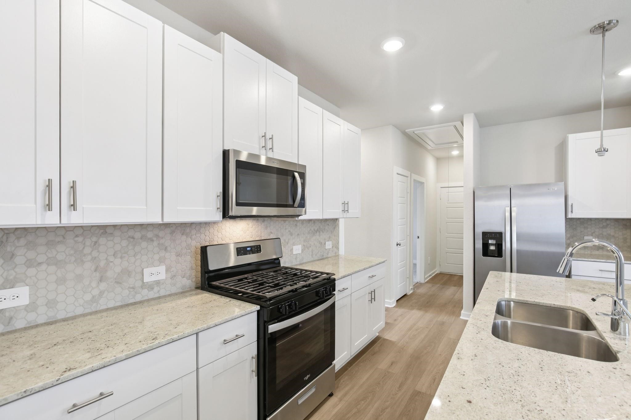 6717 Chinapkin Lane Conroe, TX 77304 - Photo 5 of 15 a kitchen with granite countertop a sink a stove and refrigerator