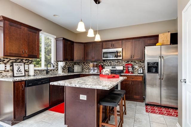 103 South Cranberry Street Bolingbrook, IL 60490 - Photo 6 of 33 a kitchen with kitchen island granite countertop a sink stove refrigerator and cabinets