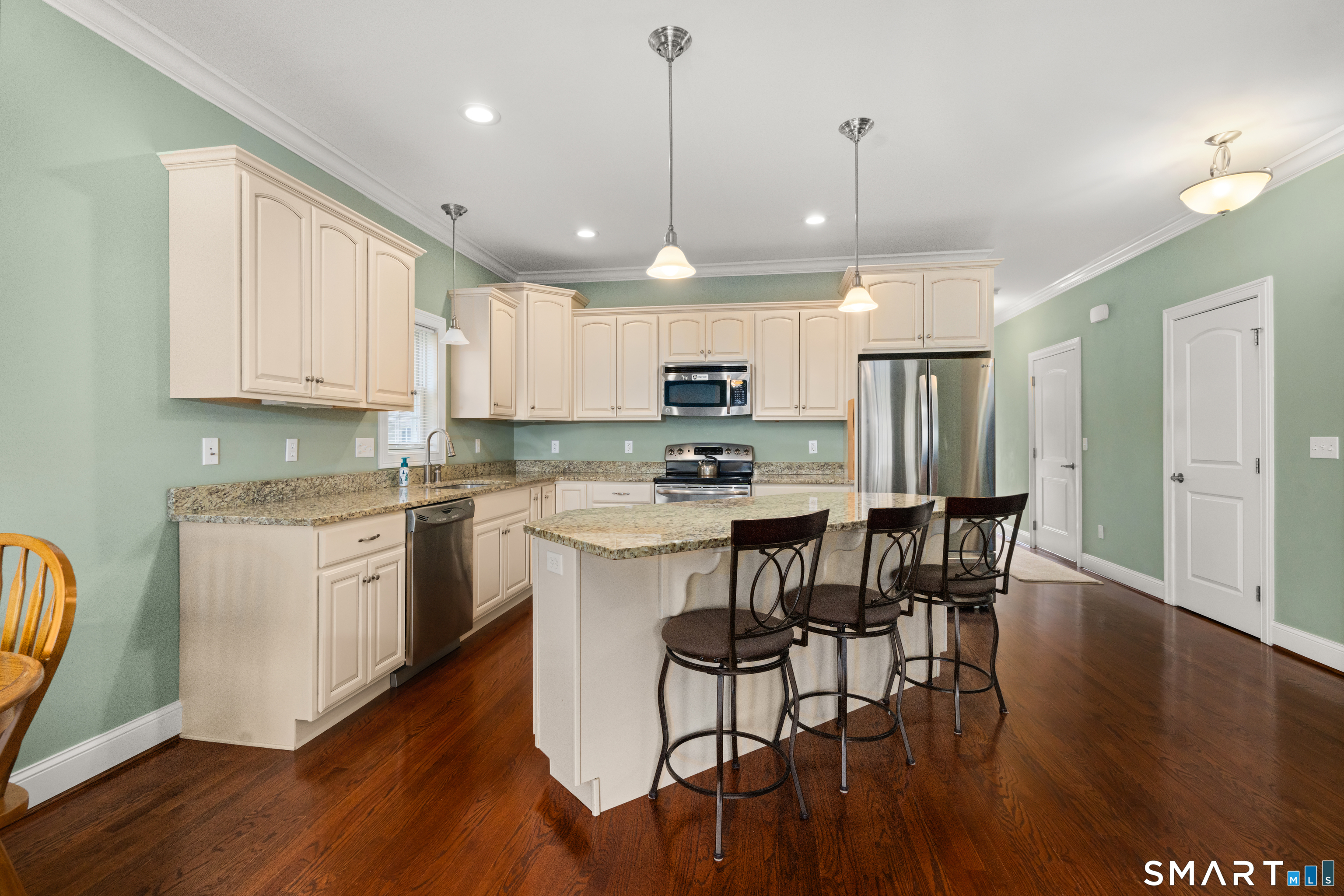24 Center Court, Unit 24 Colchester, CT 06415 - Photo 9 of 36 a kitchen with stainless steel appliances granite countertop a stove top oven a refrigerator a sink and a dining table with wooden floor
