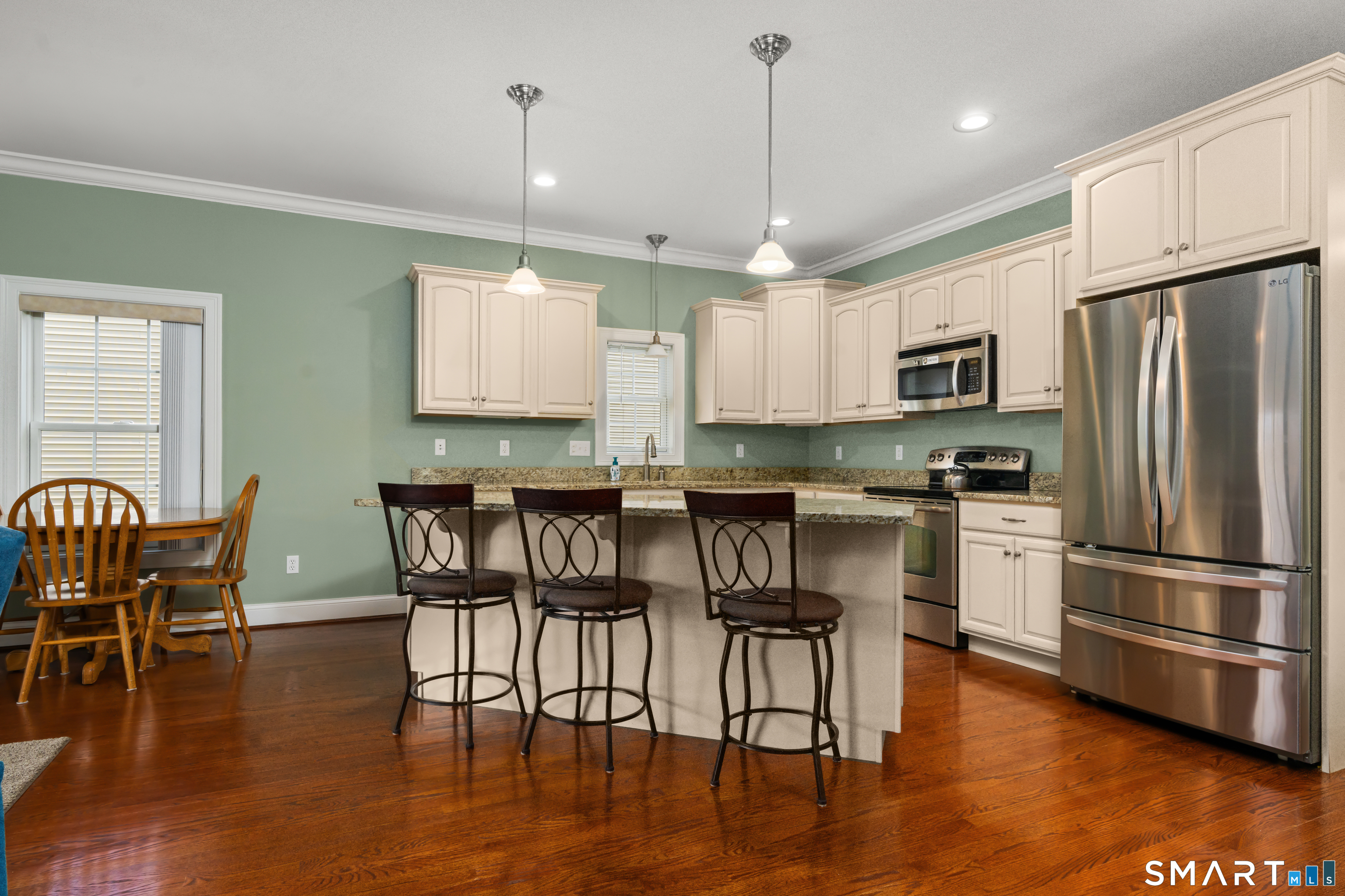 24 Center Court, Unit 24 Colchester, CT 06415 - Photo 10 of 36 a kitchen with stainless steel appliances granite countertop a stove a refrigerator a kitchen island a dining table and chairs with wooden floor