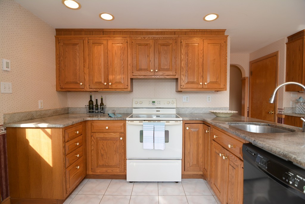 6 Cardinal Road Stoneham, MA 02180 - Photo 9 of 27 a kitchen with stainless steel appliances granite countertop a sink stove and cabinets
