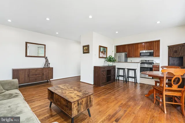 a living room with stainless steel appliances kitchen island granite countertop a couch a dining table and chairs