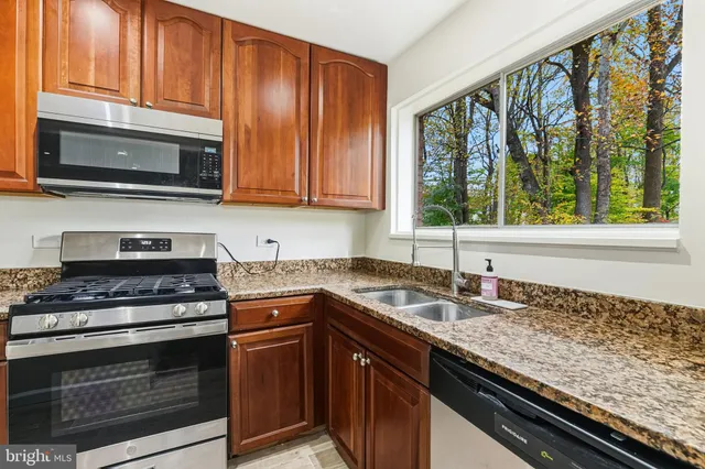 a kitchen with granite countertop stainless steel appliances a stove sink and cabinets