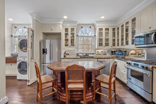 a kitchen with stainless steel appliances granite countertop a dining table chairs refrigerator and sink