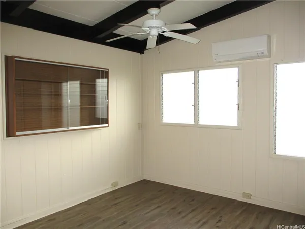 a view of empty room with wooden floor and fan