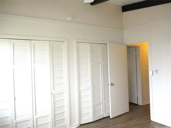 a view of an empty room with wooden floor and closet