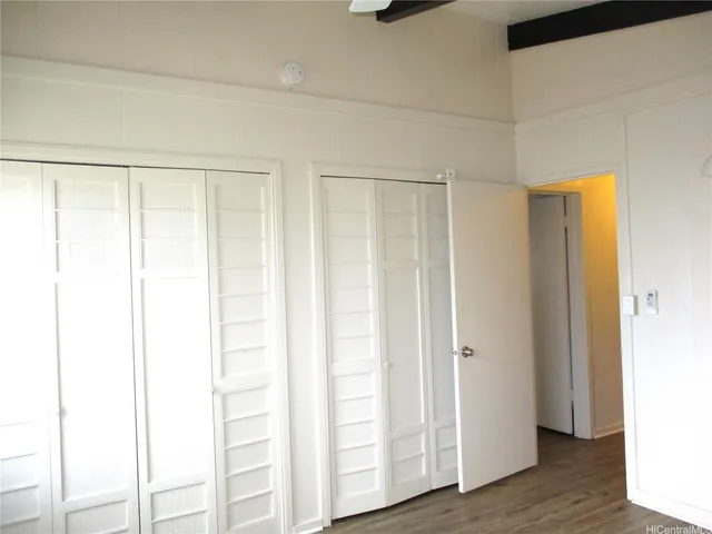 a view of an empty room with wooden floor and closet