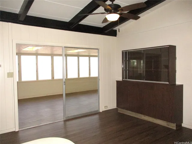 an empty room with wooden floor fan and windows