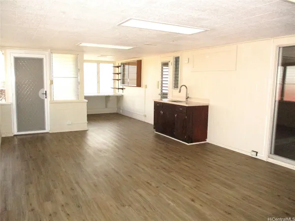 a view of a big room with wooden floor and windows