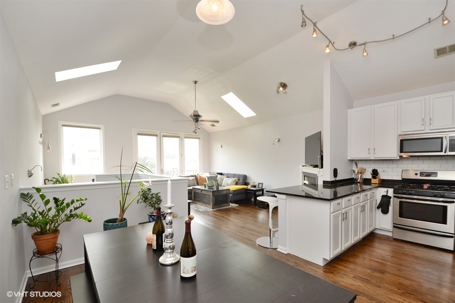 2508 West Division Street, Unit 3 Chicago, IL 60622 - Photo 2 of 10 a kitchen with stainless steel appliances kitchen island granite countertop a stove a sink dishwasher a dining table and chairs with wooden floor