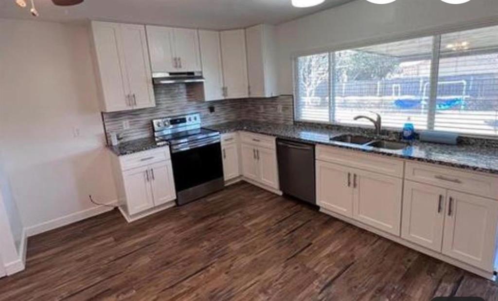 4422 Galaxie Road Garland, TX 75044 - Photo 6 of 11 Kitchen featuring white cabinetry, wood-finish flooring, stainless steel appliances, granite countertops, and a tiled backsplash