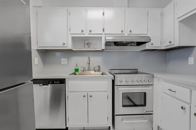 a kitchen with stainless steel appliances granite countertop white cabinets stove top oven and sink