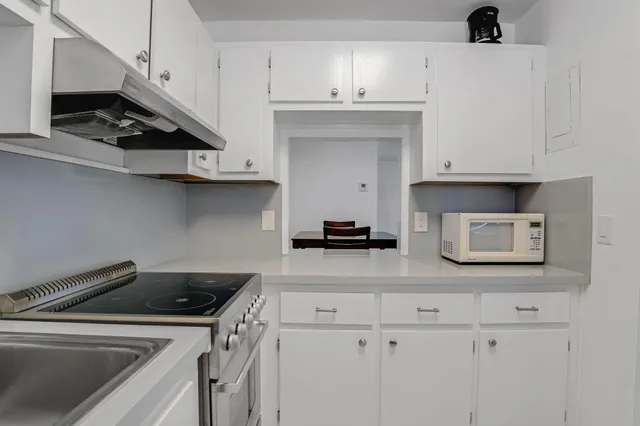 a kitchen with white cabinets and appliances