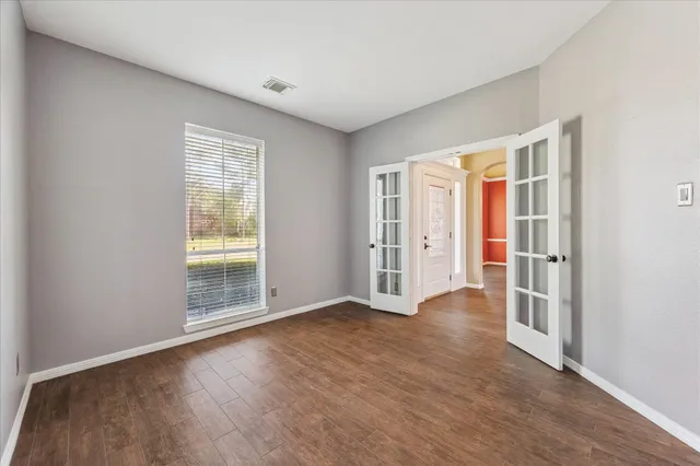 an empty room with wooden floor and windows