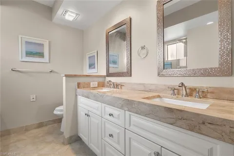a bathroom with a granite countertop sink mirror and a toilet