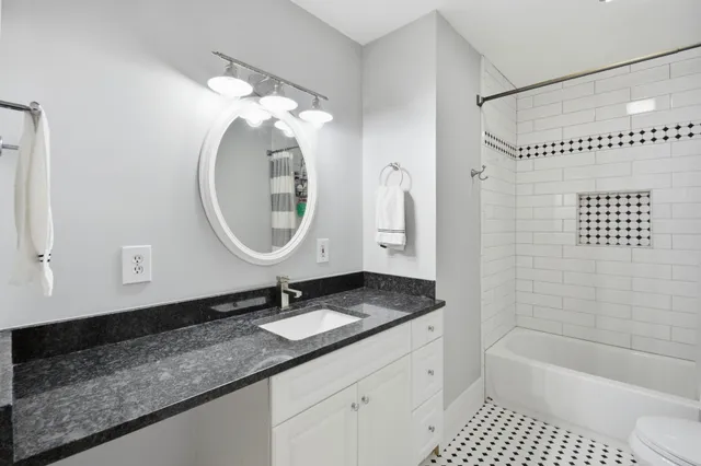 a bathroom with a granite countertop sink a mirror a vanity and bathtub