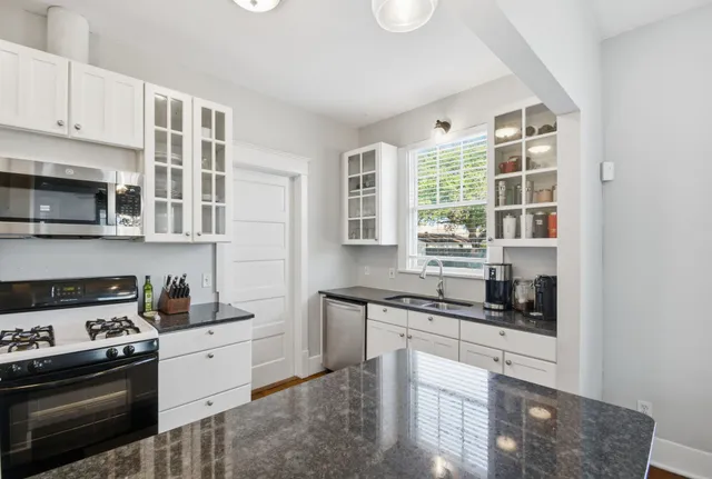 a kitchen with stainless steel appliances granite countertop a stove a sink and a microwave