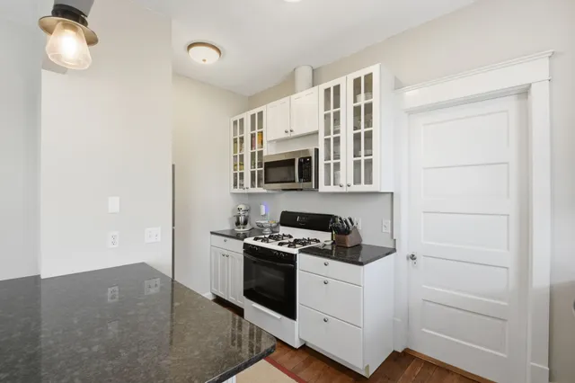a kitchen with granite countertop white cabinets and appliances