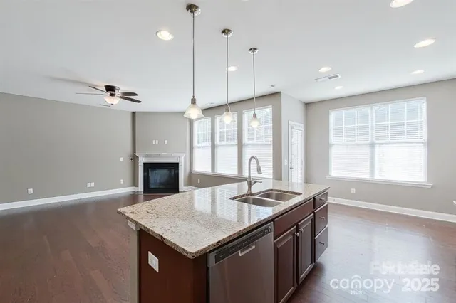 a kitchen with a stove center island a sink dishwasher and a fireplace with wooden floor